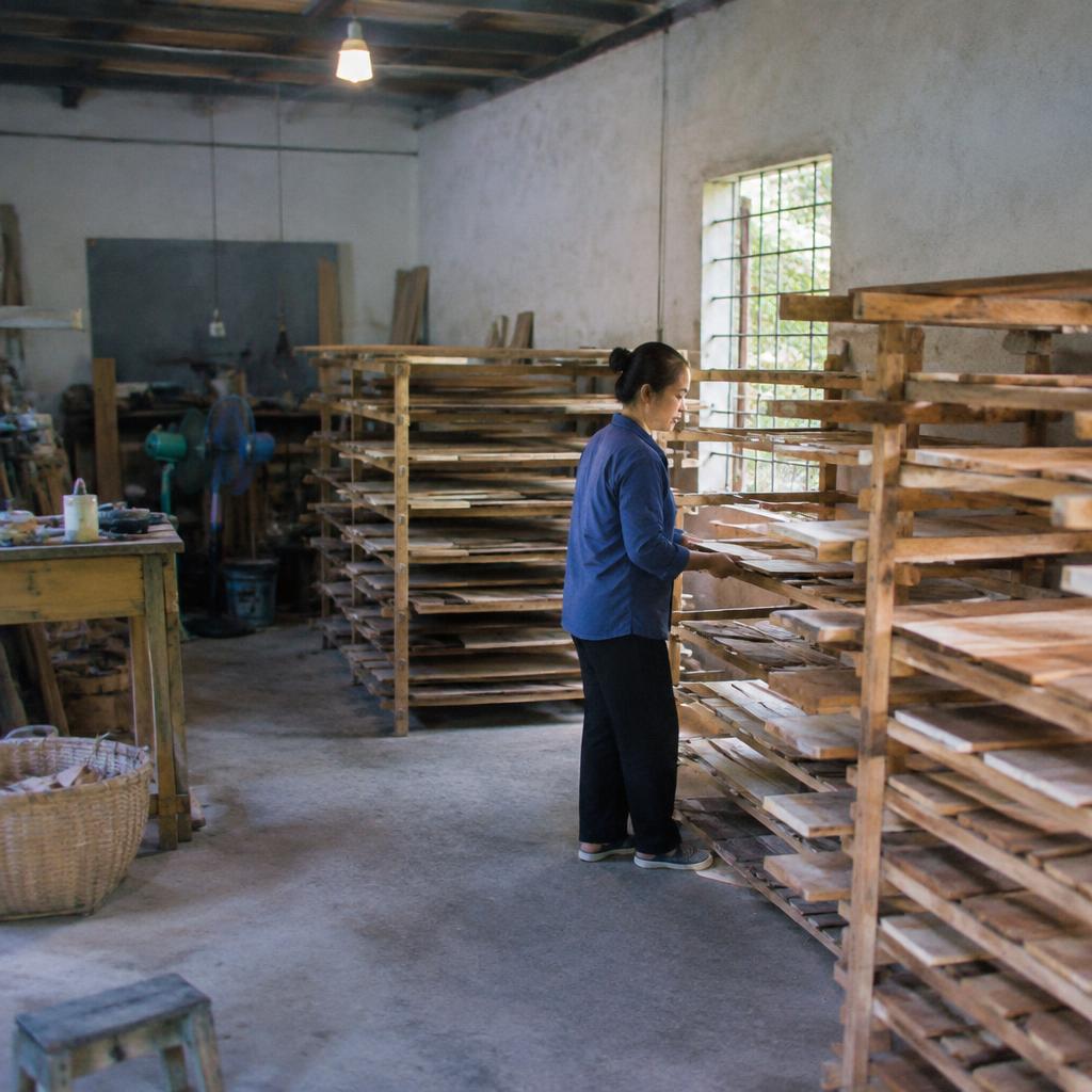 Từng tấm gỗ được xếp chồng lên nhau trong một buồng sấy lớn, có các bóng nhiệt hồng ngoại.
